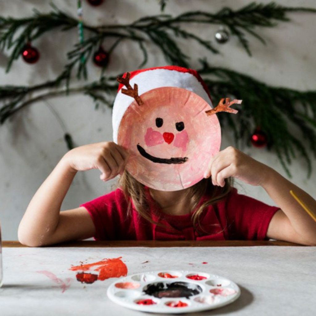 An image of a child with a paper craft reindeer.