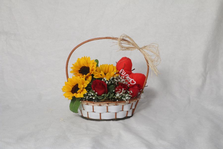 An image of flowers and cushion in a Valentine themed gift basket. 